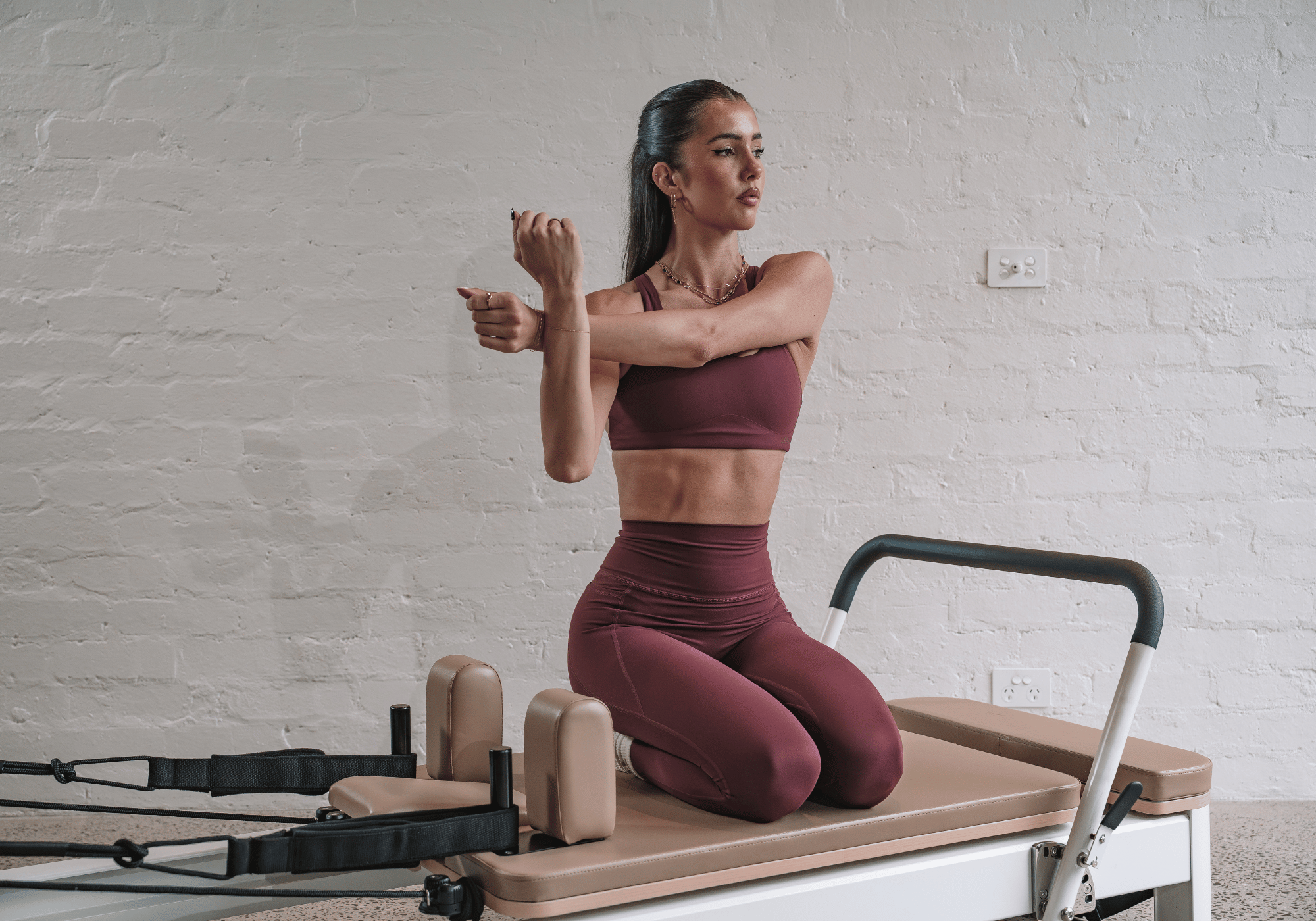 Woman on a Studio Reformer Doing a Cross-arm Shoulder Stretch