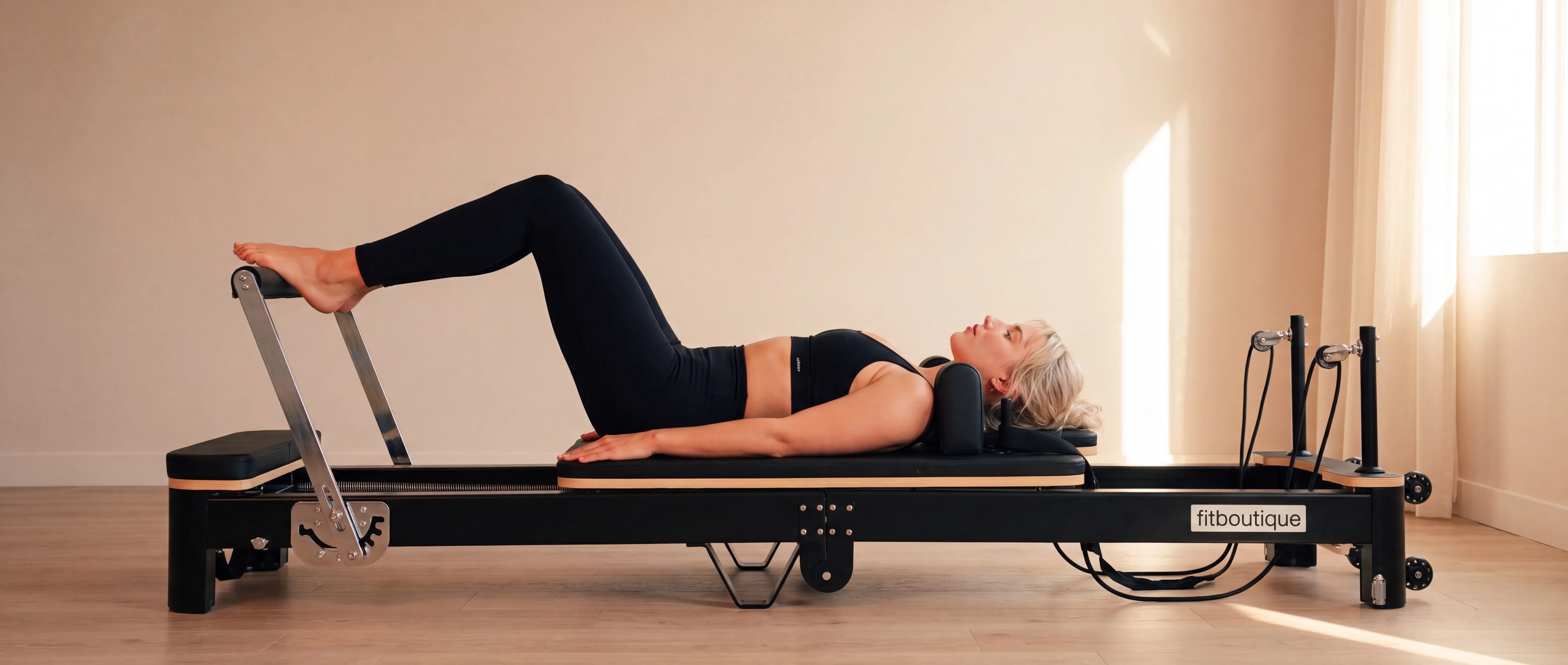 Petite woman training on the FitBoutique Ivory foldable reformer in a small space